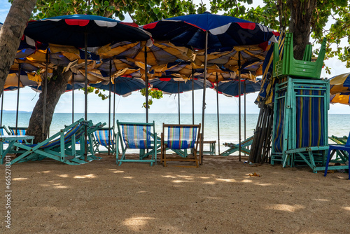 Wallpaper Mural On the seashore there are sun loungers and blue umbrellas against the background of the sky with clouds. Umbrellas are inserted into the sand of a sandy beach. Torontodigital.ca