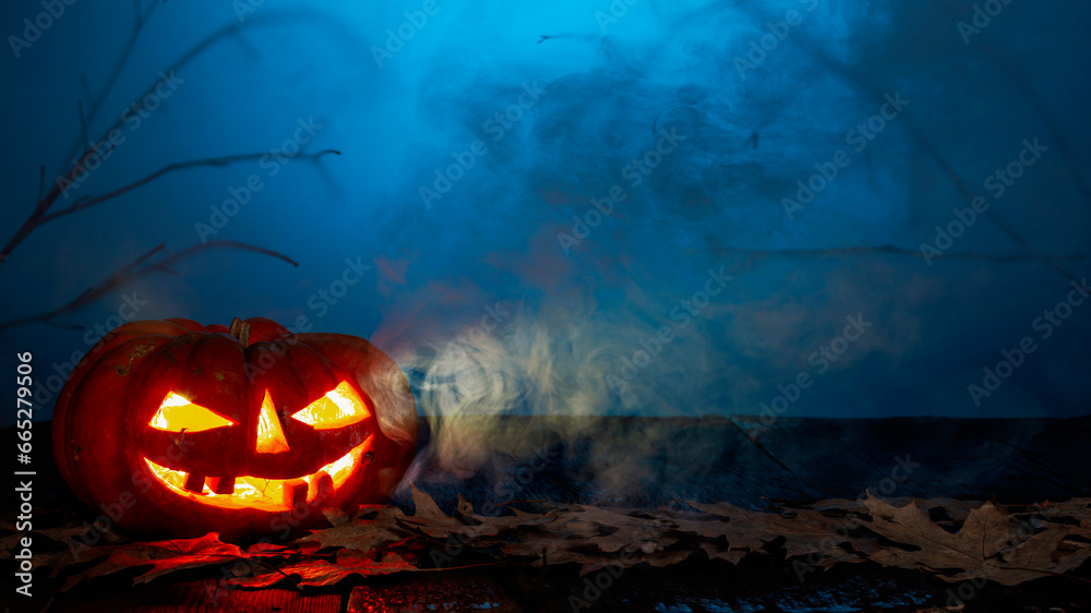 Naklejka premium Halloween pumpkin on a wooden background in a spooky atmosphere with candles and smoke