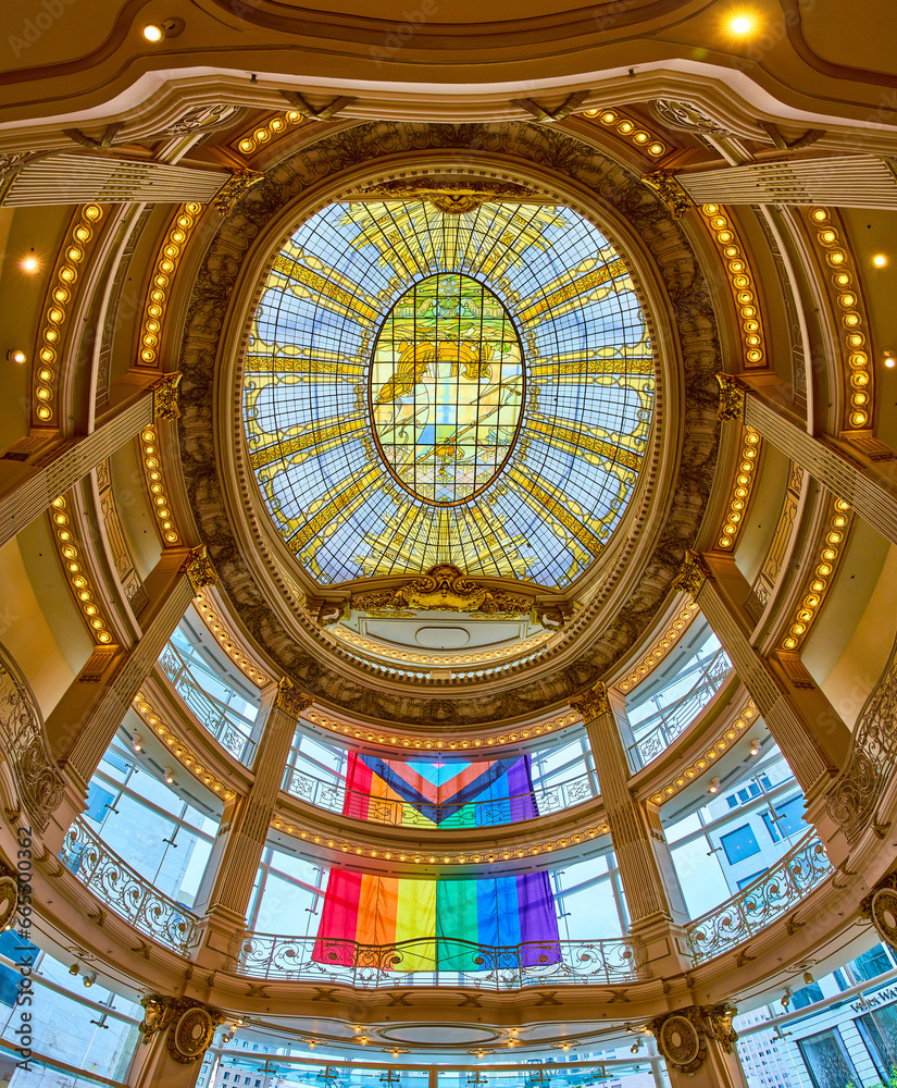 Giant pride flag on outside of window on domed golden building with stained glass ceiling panorama