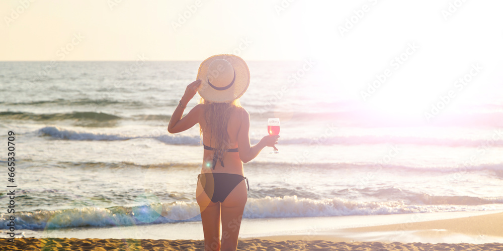 Woman with cocktail on the beach at sunset
