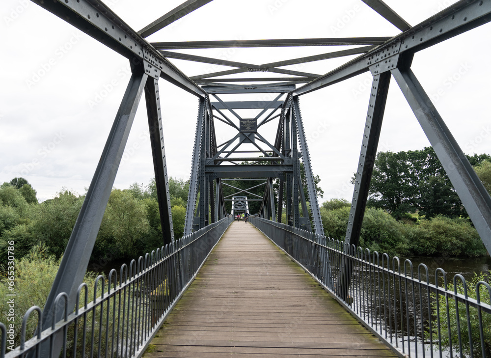 walking across a steel foot bridge across the River Eden, near Carlisle, Cumbria