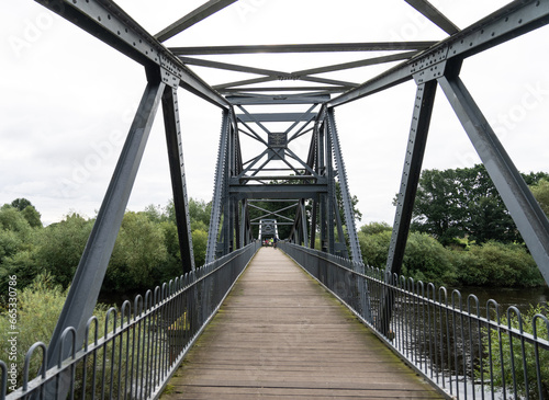 walking across a steel foot bridge across the River Eden  near Carlisle  Cumbria