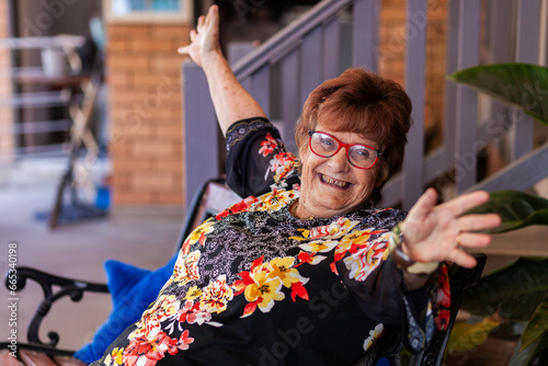 Joyful old lady with hand up in happiness photo