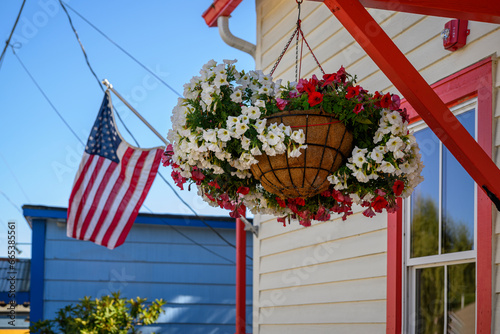 Beautiful flowers in a hanging basket and American flag flying outside the house. Poulsbo. Washington State. photo