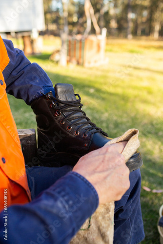 workers hands putting protective polish on work boot in backyard of home photo