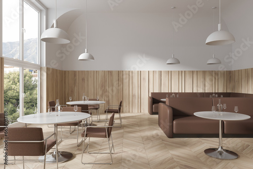 Elegant cafe interior with dinner table and brown leather sofa, panoramic window