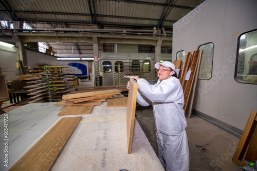 A female worker prepares a sheet of wood for subsequent painting