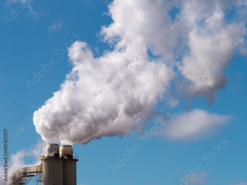 Plumes of steam rising from industrial chimneys into a blue sky photo
