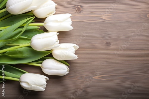 White tulips on wood table.