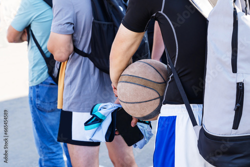 Young guys with a basketball in their hands. The school team trains outdoors. Amateur athletes wait their turn before the match. Close-up. Unrecognizable man