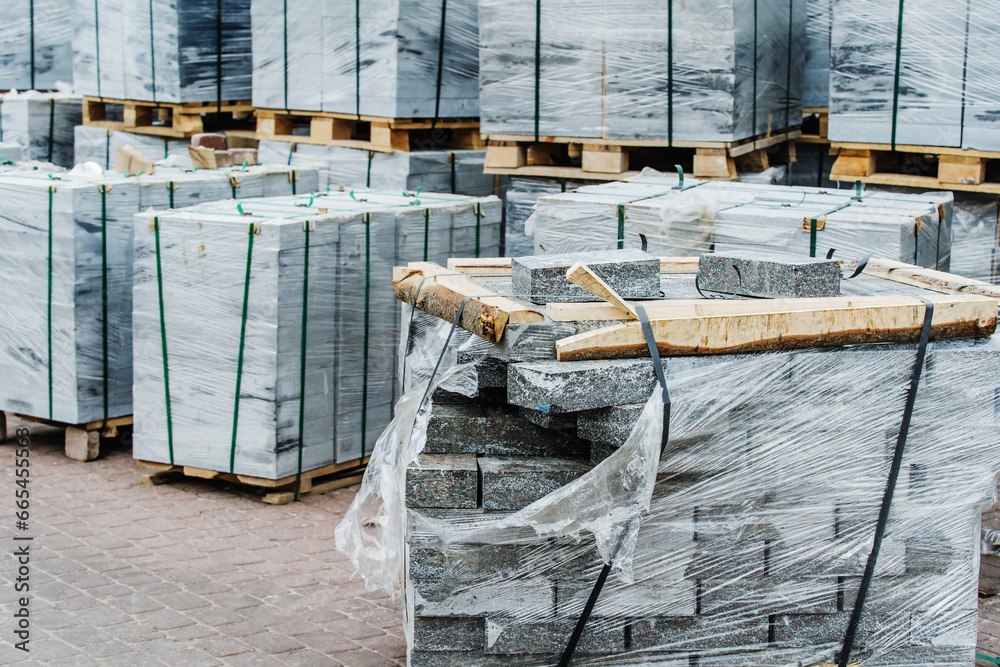 Marble paving stones in packages in the warehouse of a construction store. The material for paving sidewalks and pedestrian paths is ready for delivery. Foreground. Selective focus
