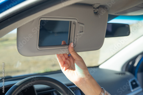 Female hand adjusting sun visor in a car. photo