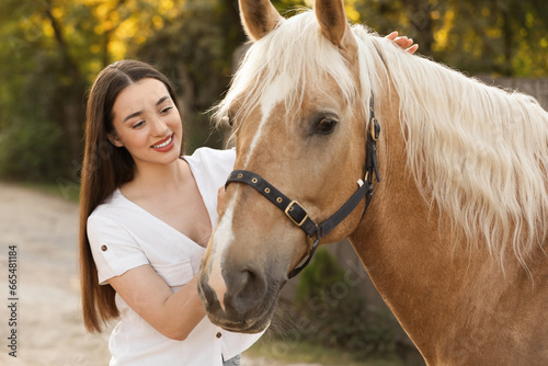 Beautiful woman with adorable horse outdoors. Lovely domesticated pet