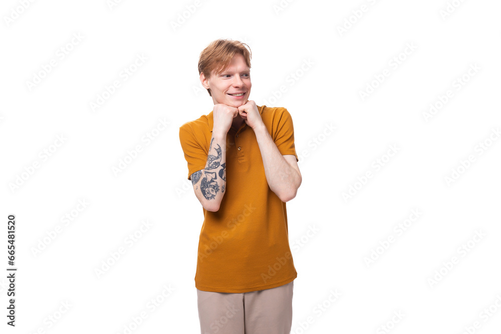 young red-haired caucasian student man with a tattoo dressed in a mustard t-shirt on a white background young red-haired caucasian student man with a tattoo dressed in a mustard t-shirt on a white background