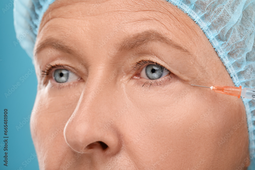 Senior woman getting facial injection on light blue background, closeup. Cosmetic surgery Senior woman getting facial injection on light blue background, closeup. Cosmetic surgery