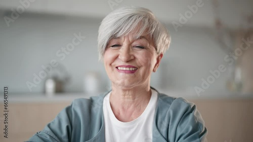 Portrait smiling mature woman. Older lady looking camera and shows white teeth. Old lady posing home. Positive single senior retired female. Gray-haired woman enjoying life, good mood. Retirement age.
