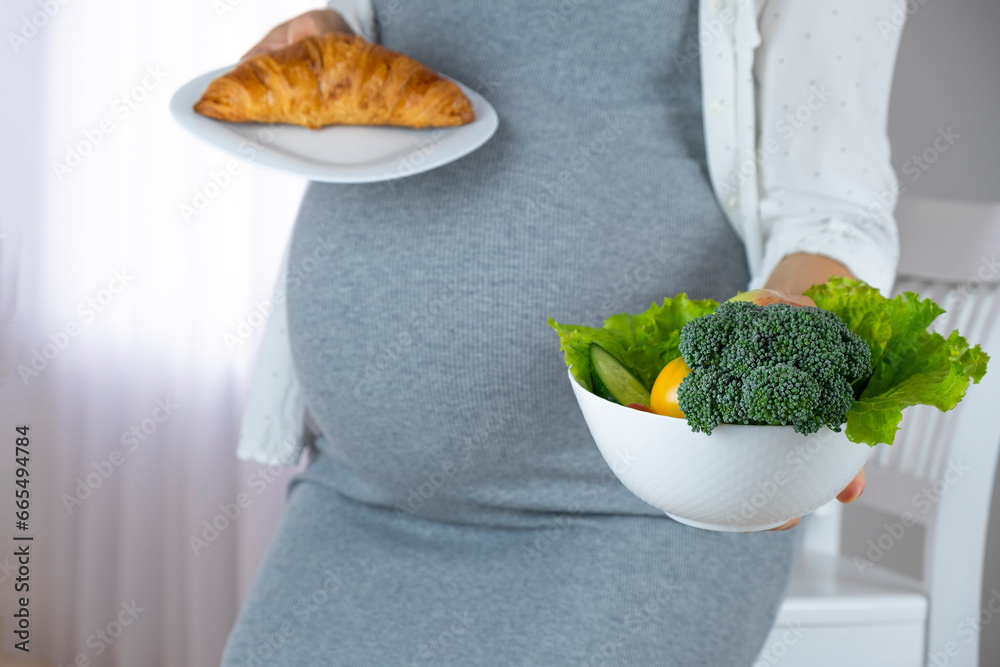 Belly of pregnant woman with bowl of vegetables and fruits and