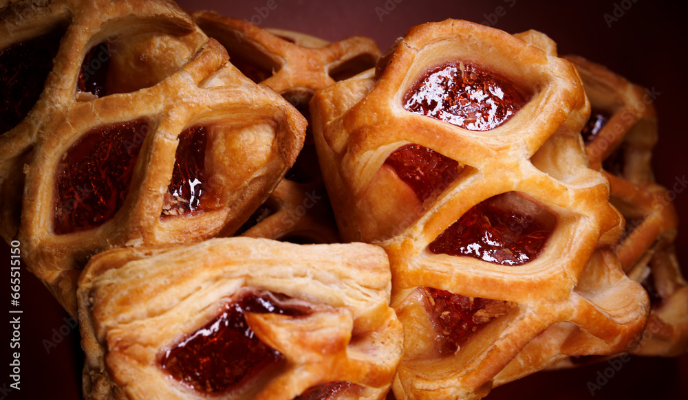 Puff pastry pastry with lingonberry jam on a dark red background. Cookies with lingonberry jam. Puff pastry pastry with lingonberry jam on a dark red background. Cookies with lingonberry jam.