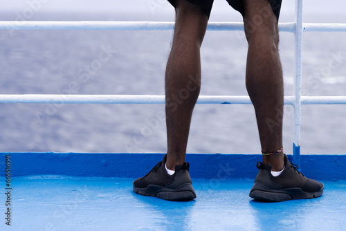 Low-angle photo of black legs in shorts and sneakers on a boat