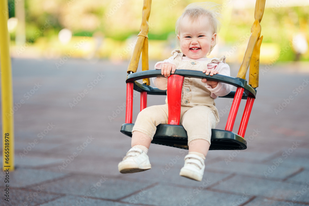 Cute little child baby on a swing in summer in the park