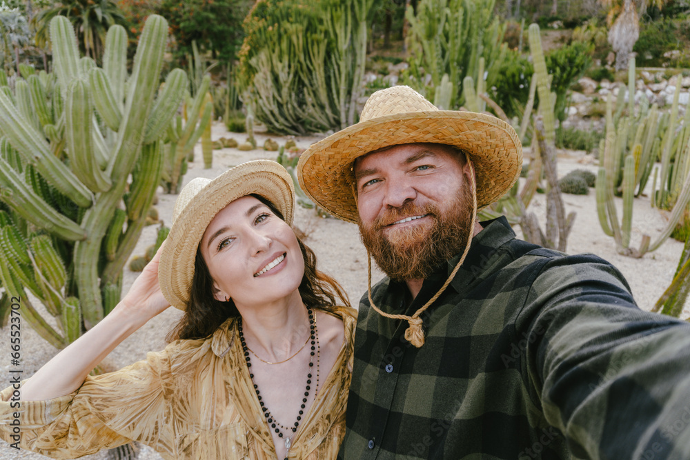 A portrait of smiling couple in a Western-style desert landscape with cacti. Selfie together during vacation in Latin America. Travel and honeymoon concept.