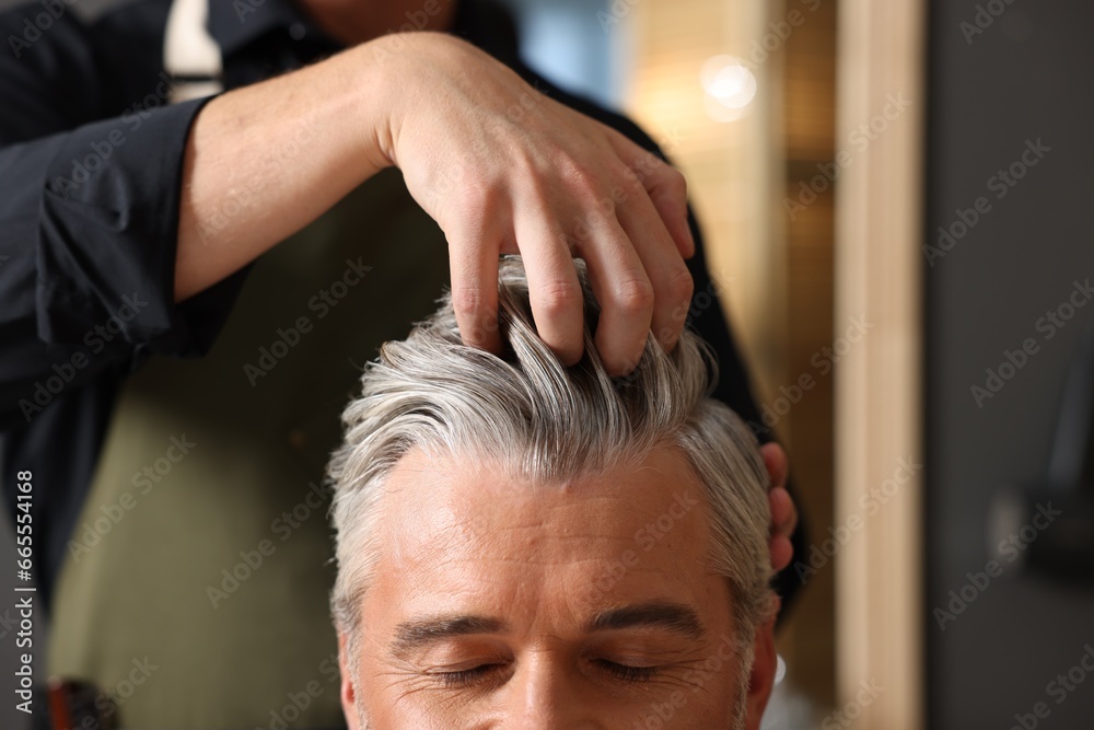 Fototapeta premium Hair styling. Professional hairdresser working with client in barbershop, closeup