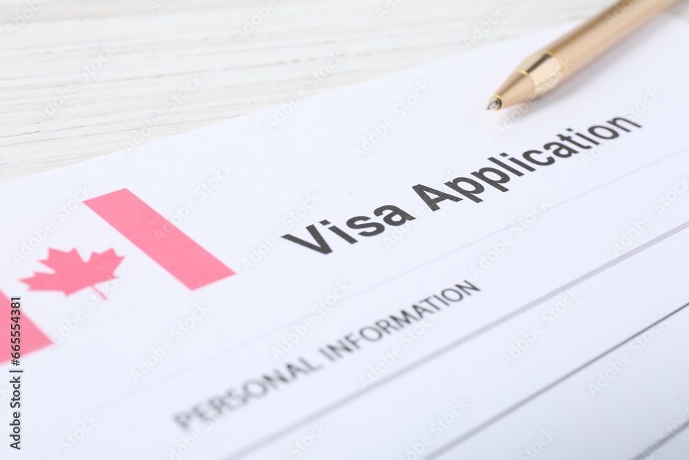 Immigration to Canada. Visa application form and pen on white wooden table, closeup