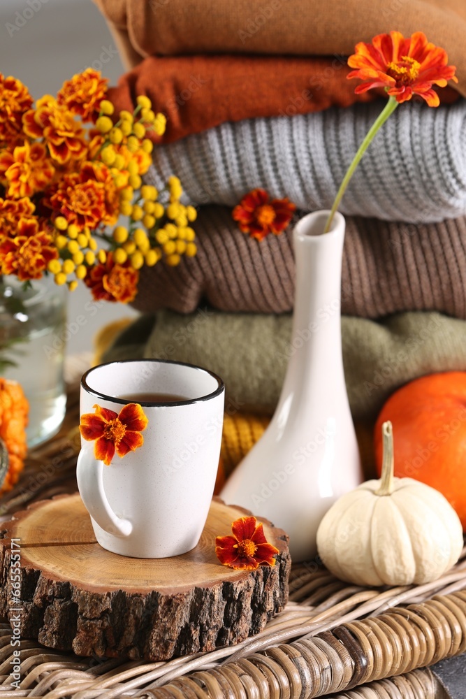 Naklejka premium Beautiful autumn composition with cup of drink and pumpkins on wicker table