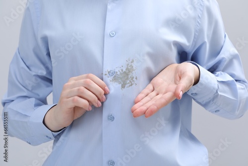 Woman showing stain on her shirt against light grey background, closeup