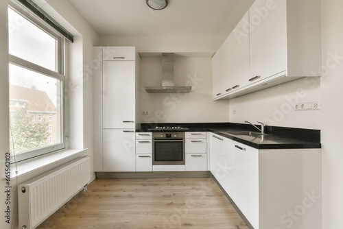 a kitchen with white cupboards and black counter tops on the floor in front of the window looking out onto the street