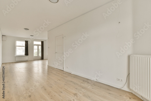 an empty room with white walls and wood flooring in the middle part of the room there is a large window