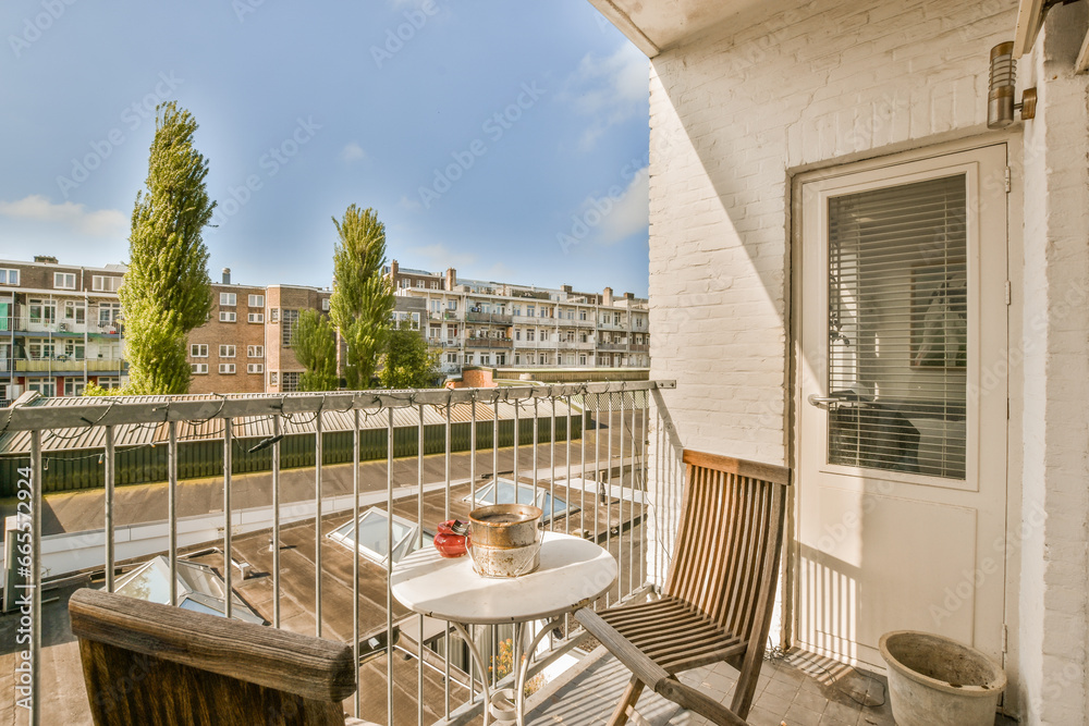 a balcony with an outside table and chairs on the left side, there is a blue sky in the background