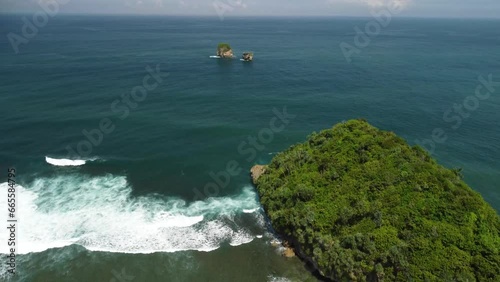 Large rolling waves and small islands at Tanjung Penyu Mas Beach, Java Island, Indonesia photo