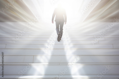 光に向かって階段を登るビジネスマン