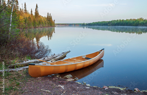 Canoe on the shore of a northern Minnesota lake at dawn on a calm day