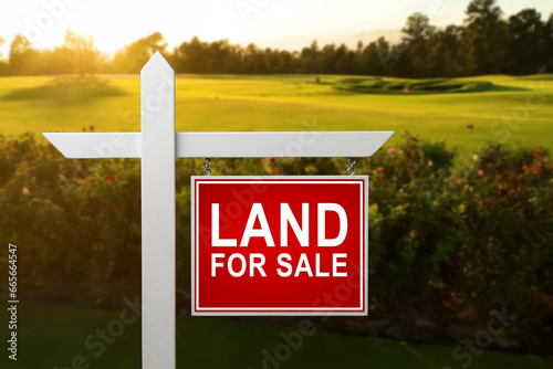 LAND FOR SALE SIGN on empty meadow - Real estate conceptual image.