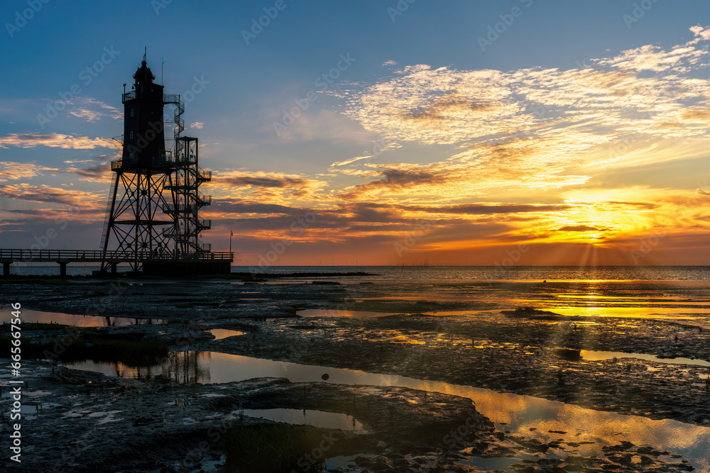 Lighthouse monument Obereversand with wadden sea at sunset Lighthouse monument Obereversand with wadden sea at sunset