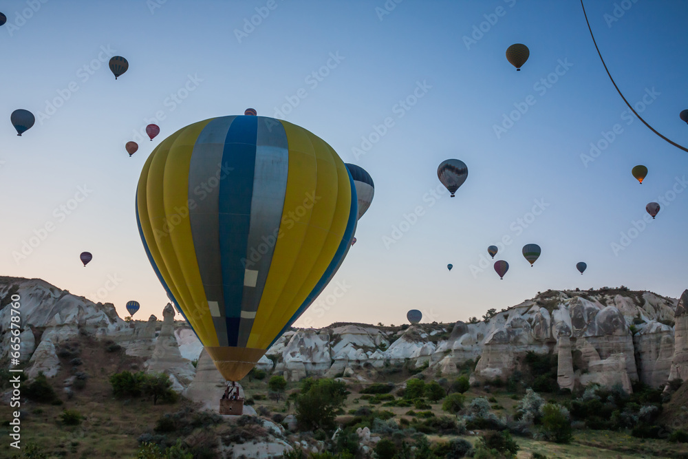 Hot air balloons flying over bizarre rock landscape in Cappadocia. Balloons fly early in the morning. Beautiful hot air balloons in the morning sky. Goreme. Turkey