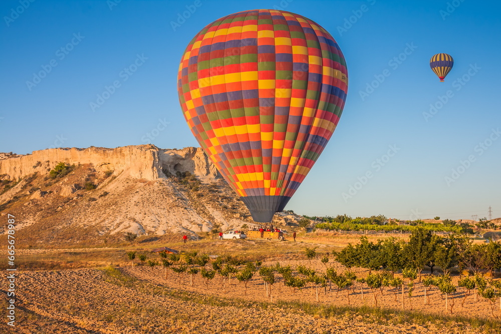 Obraz premium Hot air balloons flying over bizarre rock landscape in Cappadocia. Balloons fly early in the morning. Beautiful hot air balloons in the morning sky. Goreme. Turkey