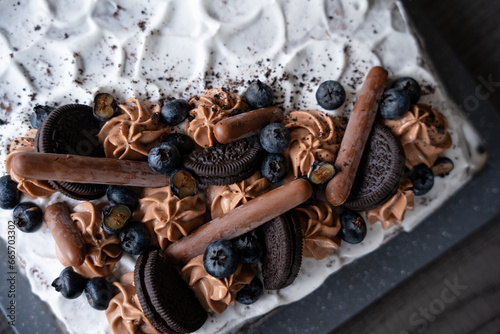 Chocolate cake decorated with blueberries, white cream cookies and chocolates