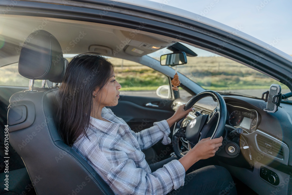 Portrait of a woman sitting in a car and  holding on to the steering wheel