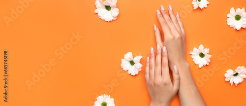 Female hands with beautiful manicure and flowers on orange background with space for text