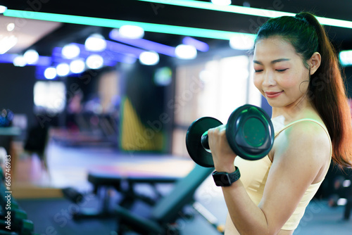 Active Asian sportswoman doing a weight training workout in indoor gym, Asian beautiful woman lifting a dumbbell.