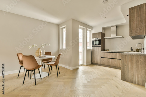 a kitchen and dining area in a house with hardwood flooring, white walls and light wood cabinets on either side © Casa imágenes