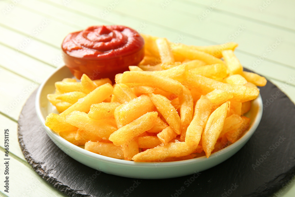 Plate with tasty french fries and bowl of ketchup on color wooden background, closeup Plate with tasty french fries and bowl of ketchup on color wooden background, closeup