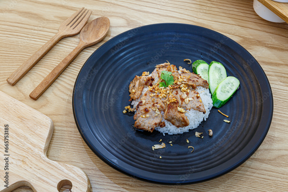 Stir-Fried Pork with Garlic and pepper with cooked thai jasmine rice in black plate, popular Thai Street food. Stir-Fried Pork with Garlic and pepper with cooked thai jasmine rice in black plate, popular Thai Street food.