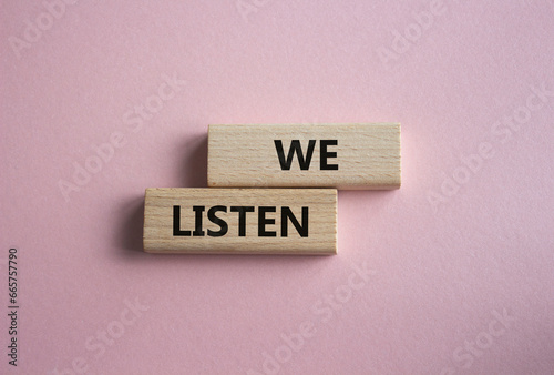 We listen symbol. Wooden blocks with words We listen. Beautiful pink background. Business and We listen concept. Copy space.
