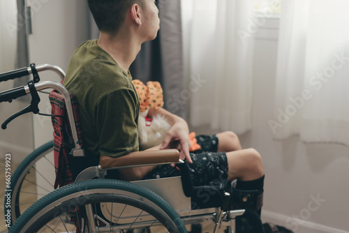 Young man with disability on wheelchair hug doll in the bedroom lonely, Depression occurs in people with disabilities who are alone at home, World mental health day and mental rehabilitation concept. photo