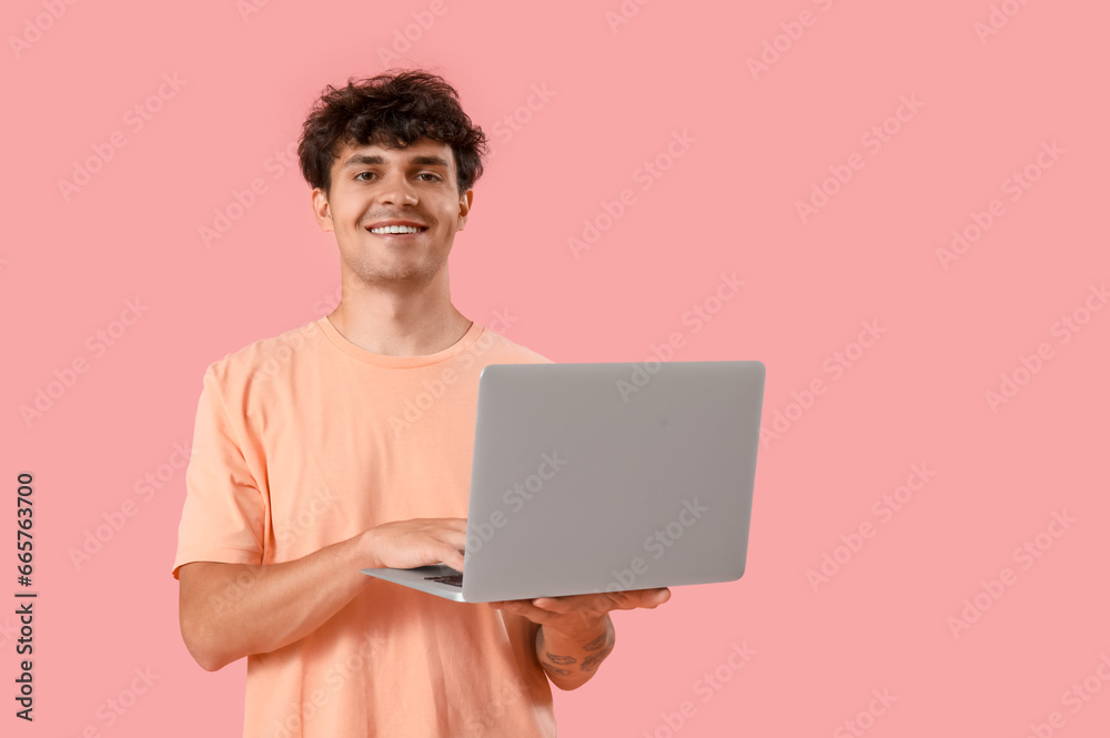 Male programmer working with computer on pink background Male programmer working with computer on pink background