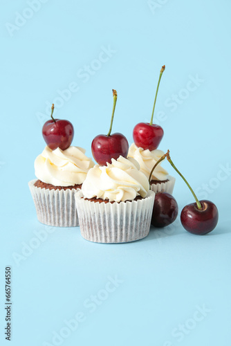 Tasty cherry cupcakes on blue background